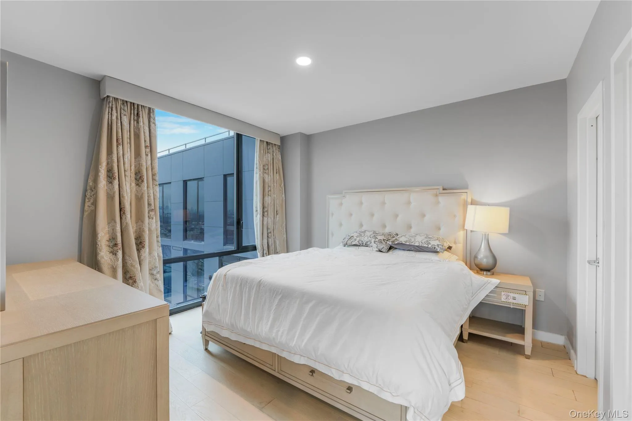 Bedroom with light wood-style floors, floor to ceiling windows, and recessed lighting Bedroom with light wood-style floors, floor to ceiling windows, and recessed lighting