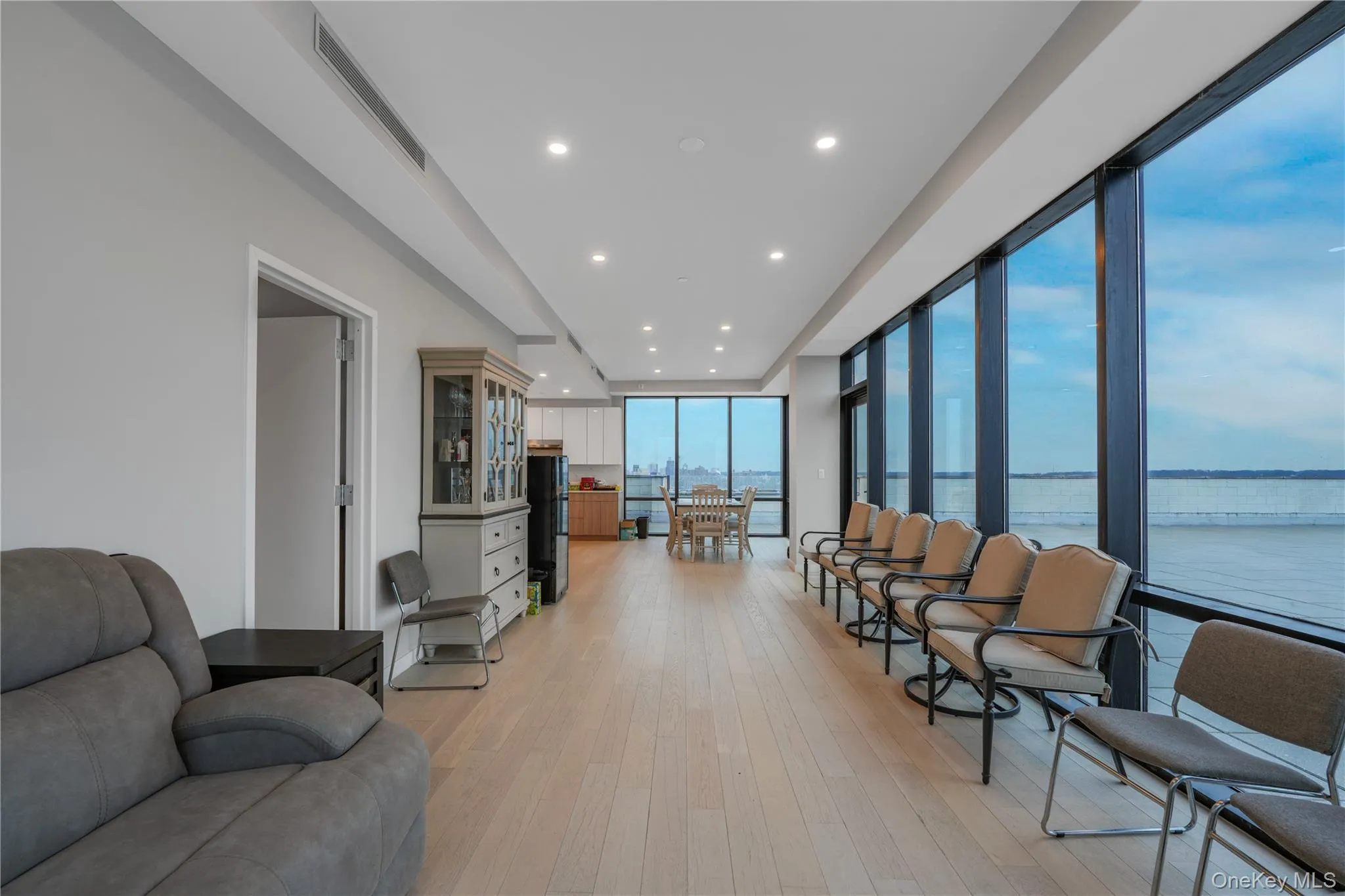 Living room featuring a wall of windows, light wood-style floors, recessed lighting, and a water view Living room featuring a wall of windows, light wood-style floors, recessed lighting, and a water view
