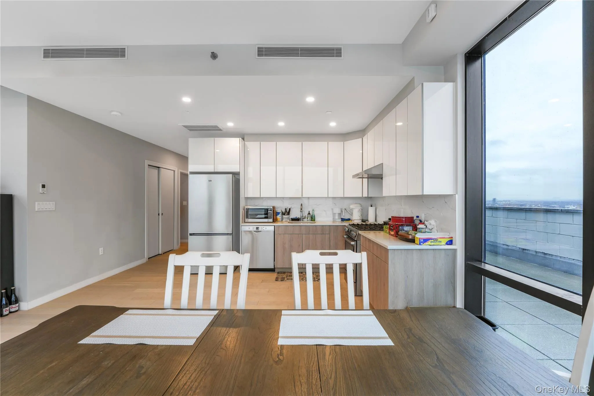 Kitchen with modern cabinets, white cabinetry, light countertops, stainless steel appliances, and recessed lighting Kitchen with modern cabinets, white cabinetry, light countertops, stainless steel appliances, and recessed lighting