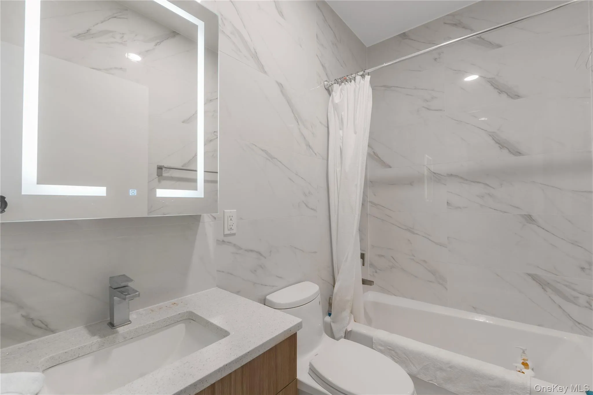 Full bathroom with vanity and a combined bath / shower with marble appearance Full bathroom with vanity and a combined bath / shower with marble appearance