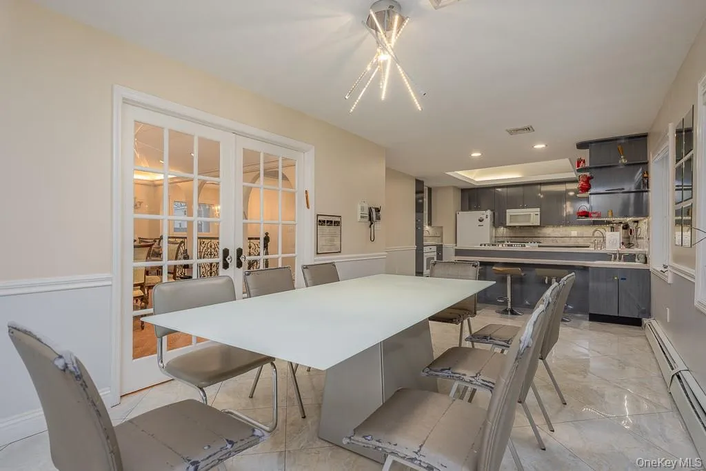 Dining area featuring a baseboard radiator, recessed lighting, french doors, and light marble finish floors Dining area featuring a baseboard radiator, recessed lighting, french doors, and light marble finish floors