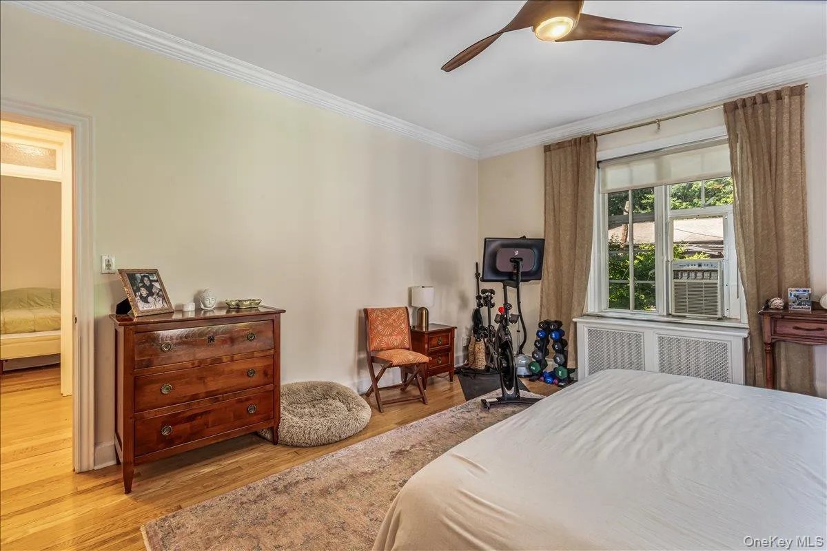 Bedroom featuring crown molding, radiator, wood finished floors, and a ceiling fan Bedroom featuring crown molding, radiator, wood finished floors, and a ceiling fan