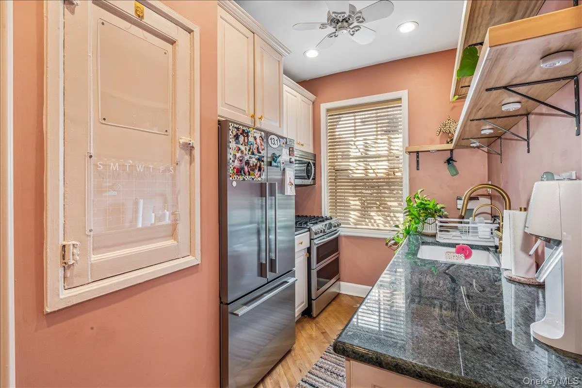 Kitchen with appliances with stainless steel finishes, dark stone countertops, ventilation hood, light wood-type flooring, and recessed lighting Kitchen with appliances with stainless steel finishes, dark stone countertops, ventilation hood, light wood-type flooring, and recessed lighting