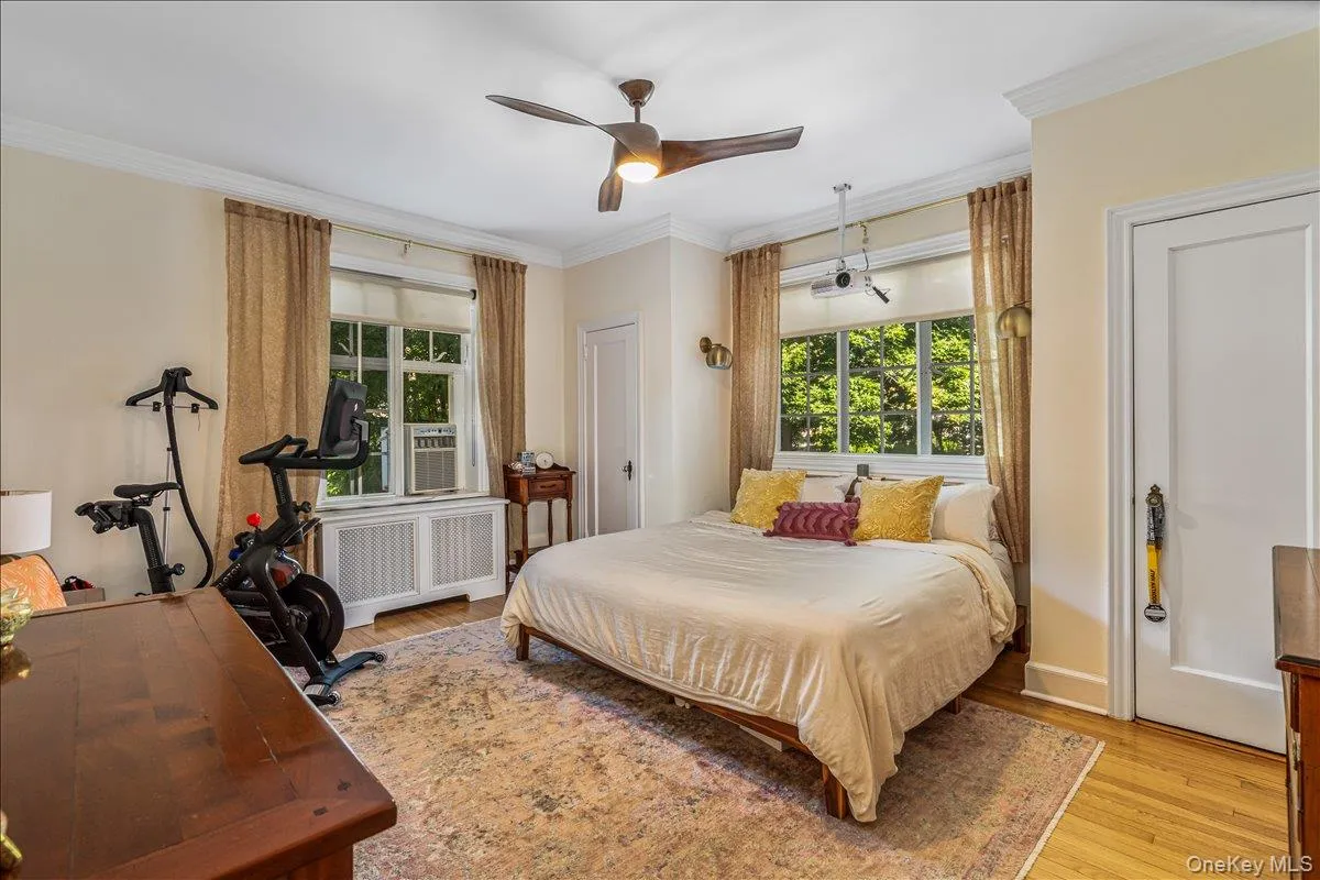 Bedroom with radiator heating unit, crown molding, light wood finished floors, ceiling fan, and cooling unit Bedroom with radiator heating unit, crown molding, light wood finished floors, ceiling fan, and cooling unit