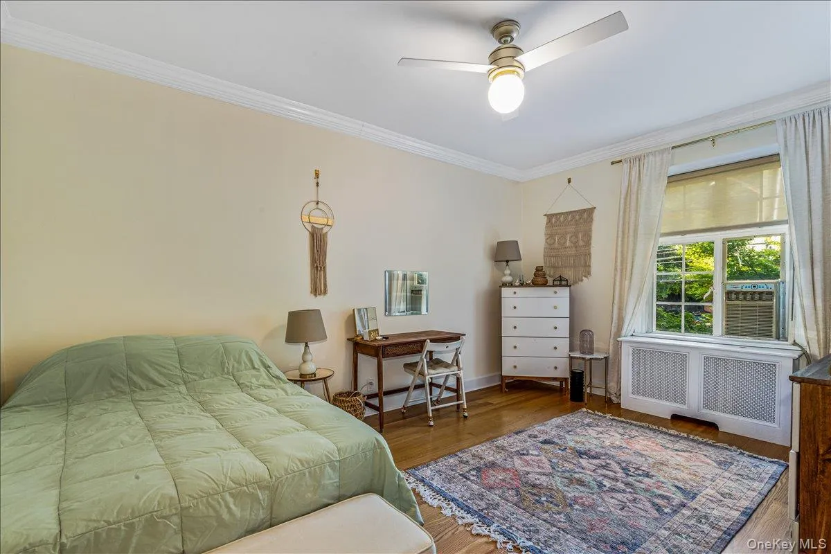 Bedroom with crown molding, wood finished floors, radiator heating unit, and ceiling fan Bedroom with crown molding, wood finished floors, radiator heating unit, and ceiling fan