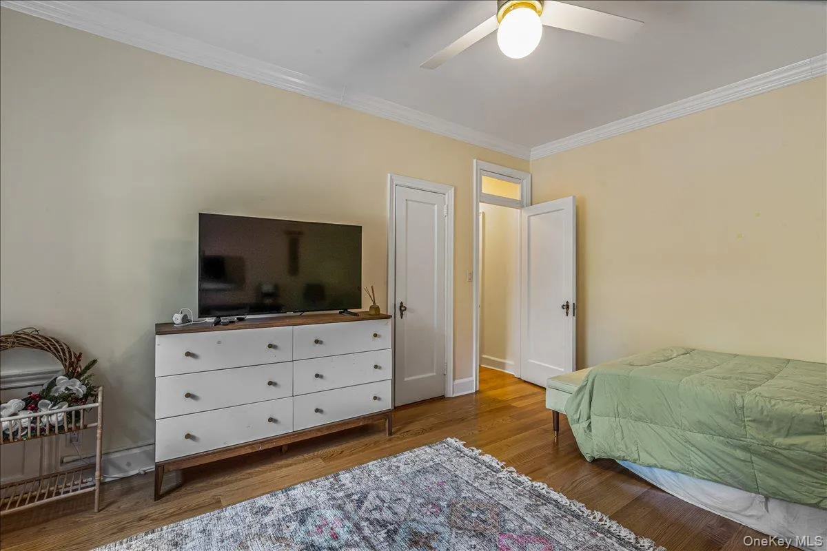 Bedroom with crown molding, wood finished floors, and a ceiling fan Bedroom with crown molding, wood finished floors, and a ceiling fan