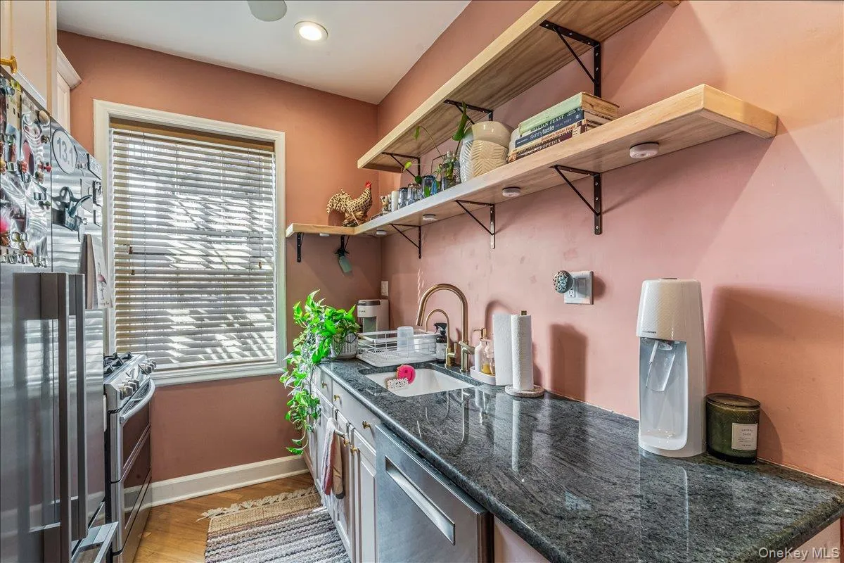 Kitchen featuring appliances with stainless steel finishes, dark stone counters, open shelves, and light wood-style floors Kitchen featuring appliances with stainless steel finishes, dark stone counters, open shelves, and light wood-style floors