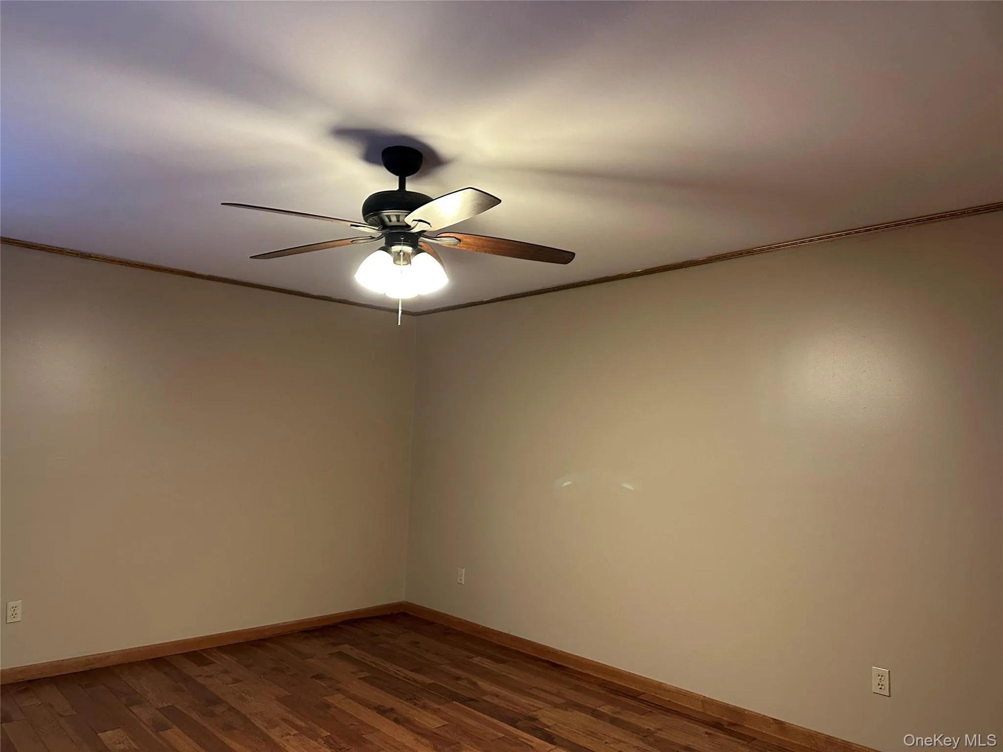 Empty room featuring crown molding, dark wood-type flooring, and ceiling fan Empty room featuring crown molding, dark wood-type flooring, and ceiling fan