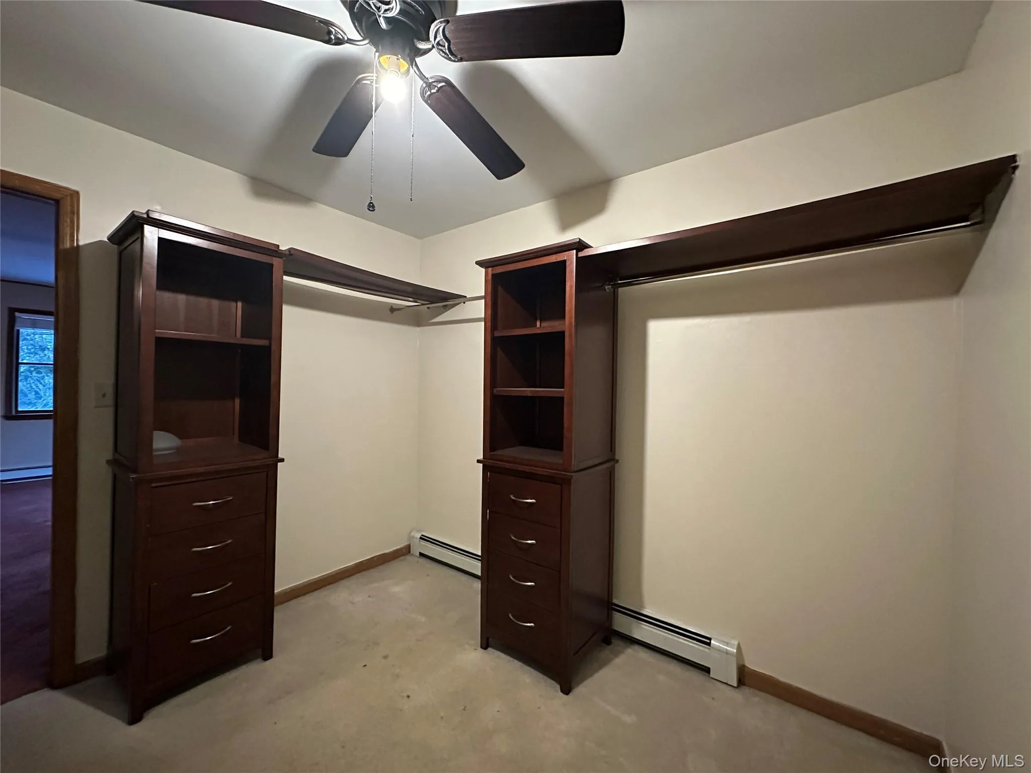 Spacious closet with a baseboard radiator and ceiling fan Spacious closet with a baseboard radiator and ceiling fan
