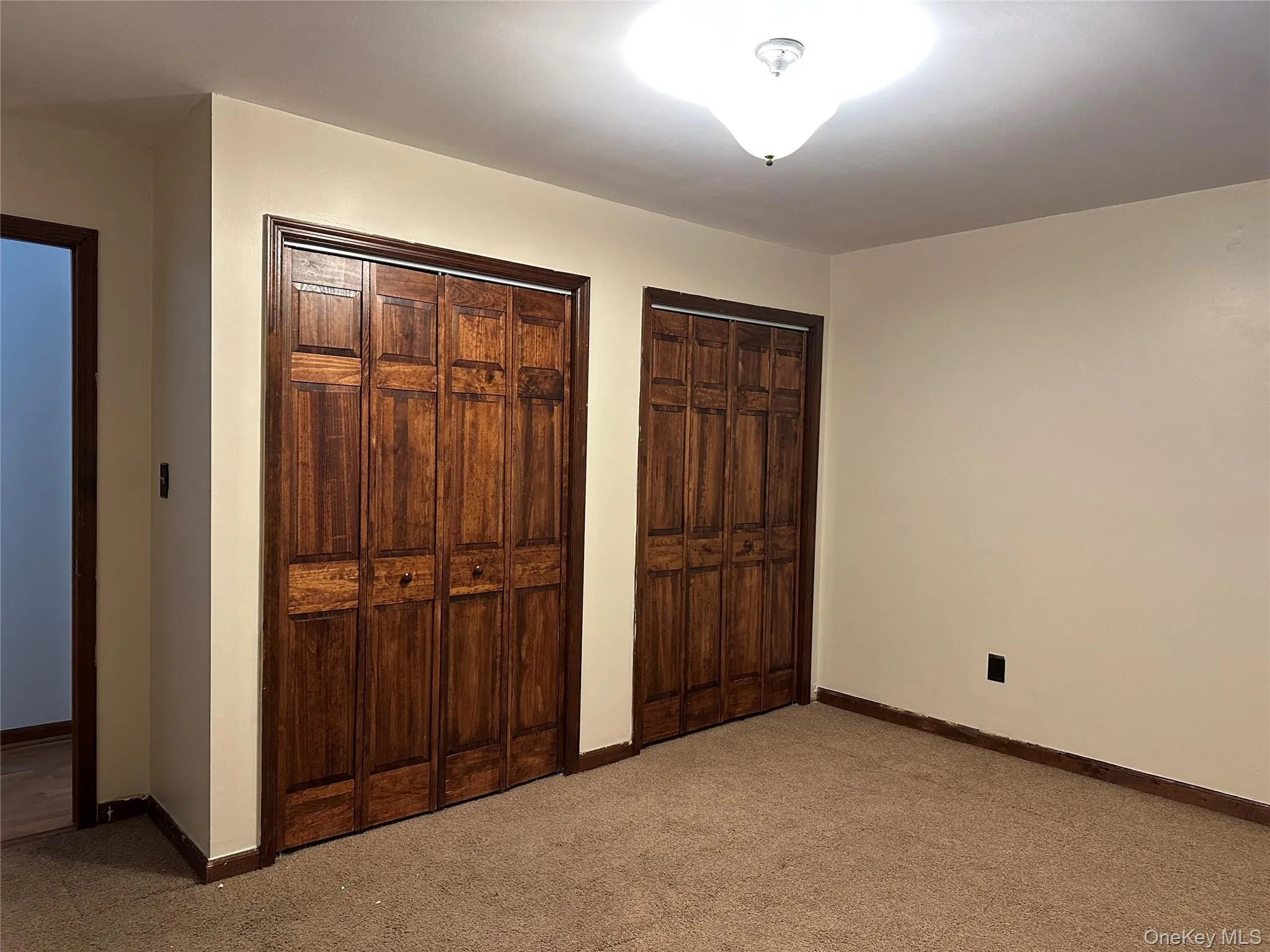 Unfurnished bedroom with two closets and carpet flooring Unfurnished bedroom with two closets and carpet flooring