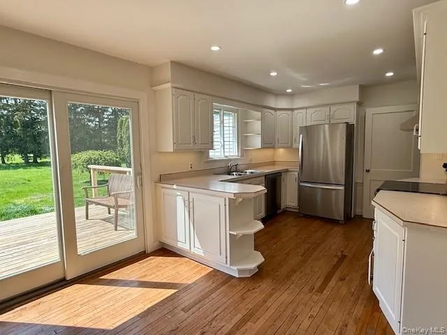 Kitchen with open shelves, light countertops, freestanding refrigerator, white cabinets, and recessed lighting Kitchen with open shelves, light countertops, freestanding refrigerator, white cabinets, and recessed lighting