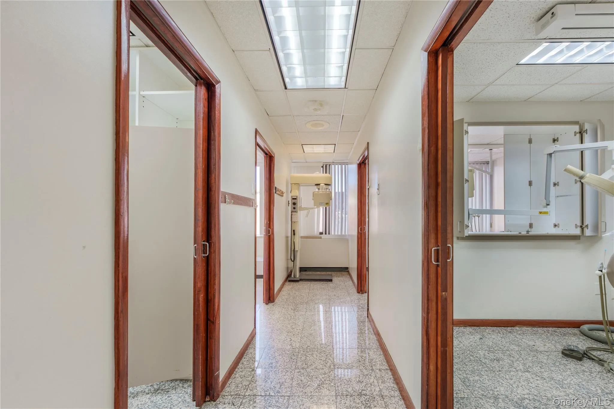 Hall featuring granite tiled floors, a drop ceiling, and cooling unit Hall featuring granite tiled floors, a drop ceiling, and cooling unit