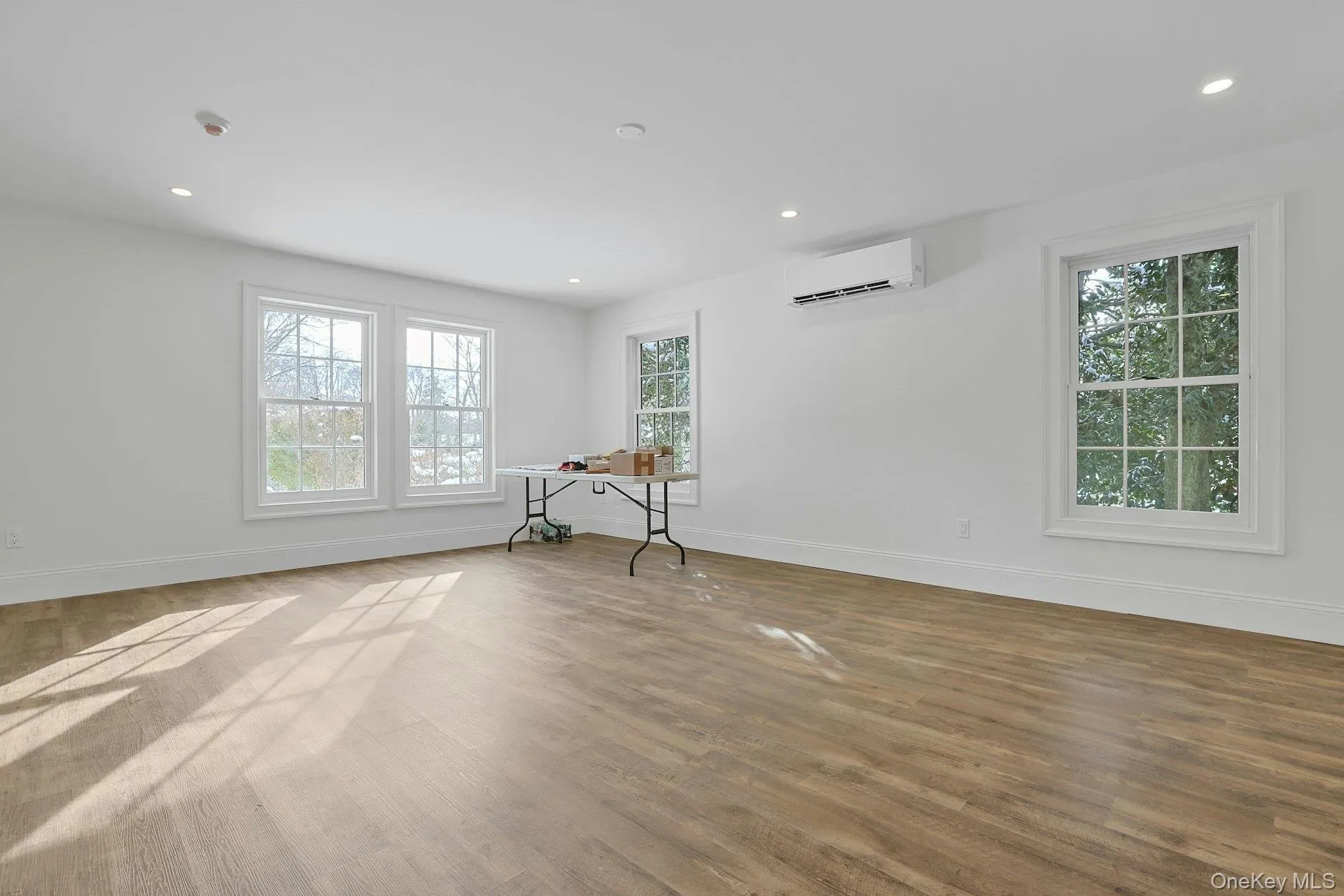 Empty room with plenty of natural light, wood finished floors, recessed lighting, and a wall unit AC Empty room with plenty of natural light, wood finished floors, recessed lighting, and a wall unit AC