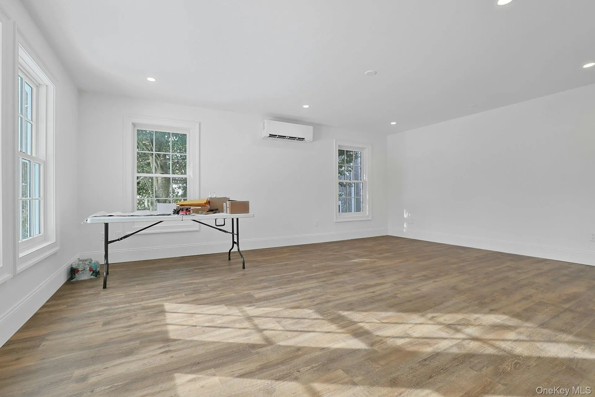 Empty room with light wood finished floors, recessed lighting, and a wall unit AC Empty room with light wood finished floors, recessed lighting, and a wall unit AC
