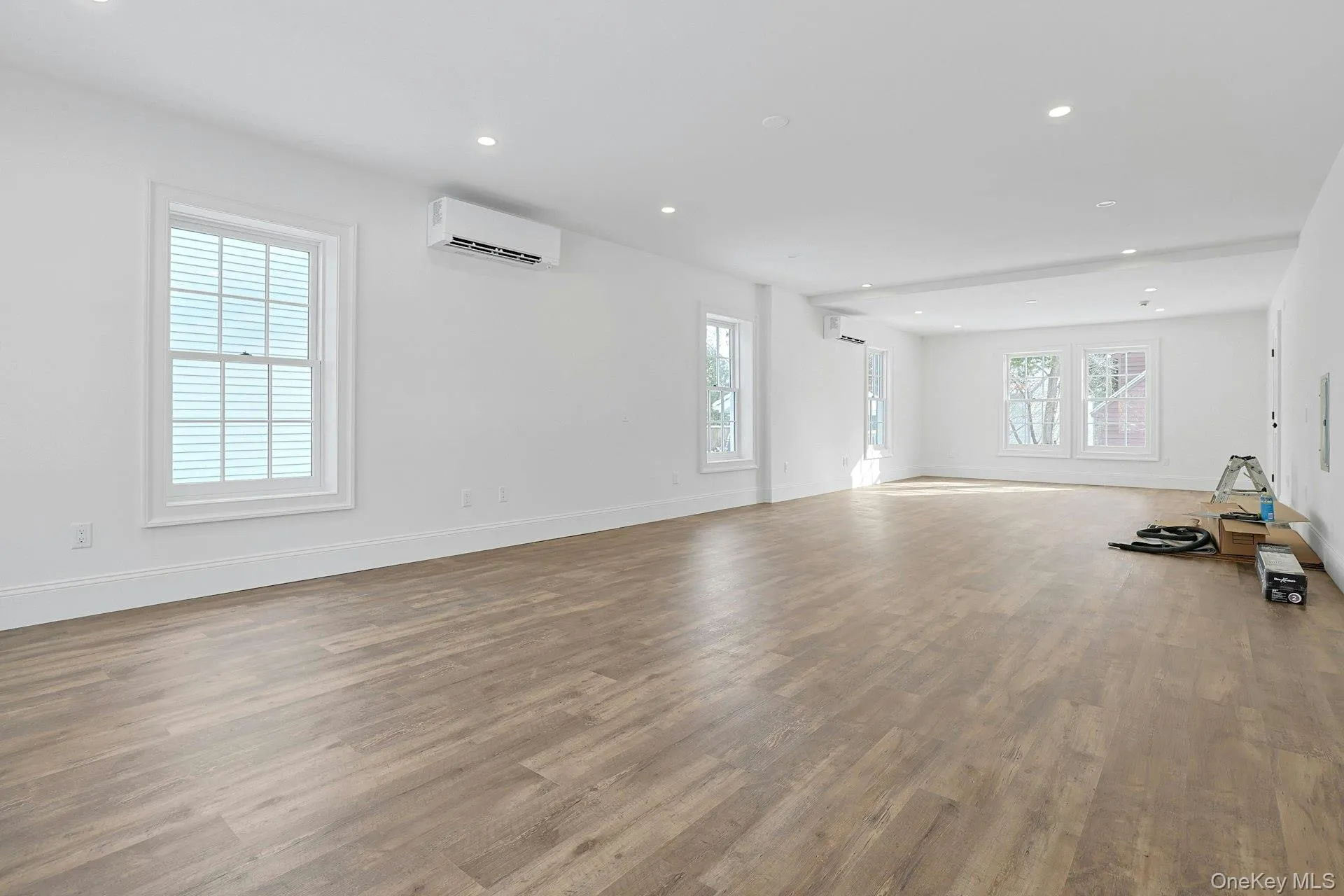 Unfurnished living room with recessed lighting, wood finished floors, and a wall mounted air conditioner Unfurnished living room with recessed lighting, wood finished floors, and a wall mounted air conditioner