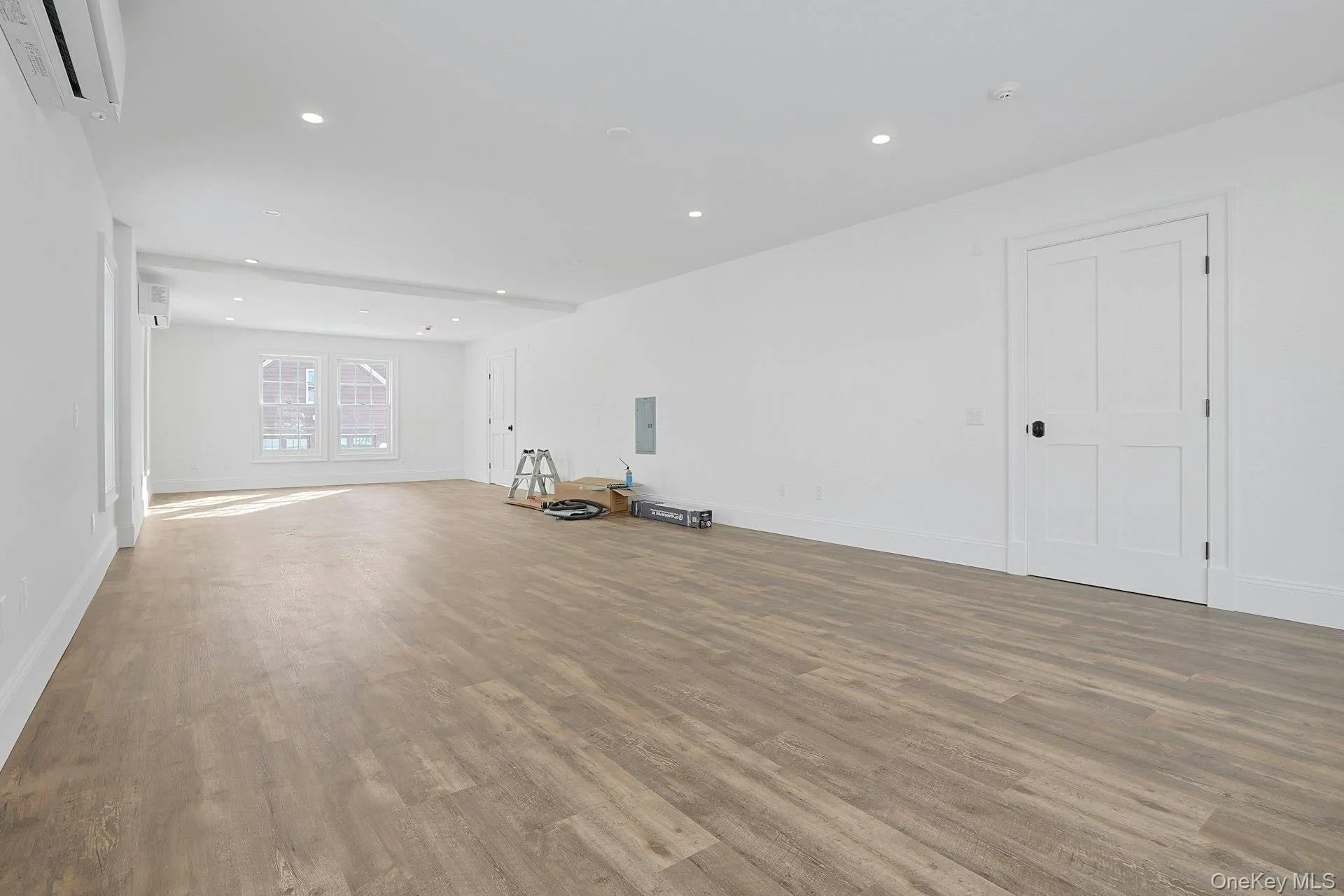 Unfurnished living room with wood finished floors, recessed lighting, a wall mounted AC, and electric panel Unfurnished living room with wood finished floors, recessed lighting, a wall mounted AC, and electric panel