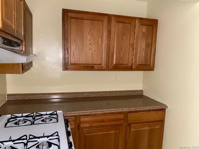 Kitchen with brown cabinets and white range with gas cooktop Kitchen with brown cabinets and white range with gas cooktop