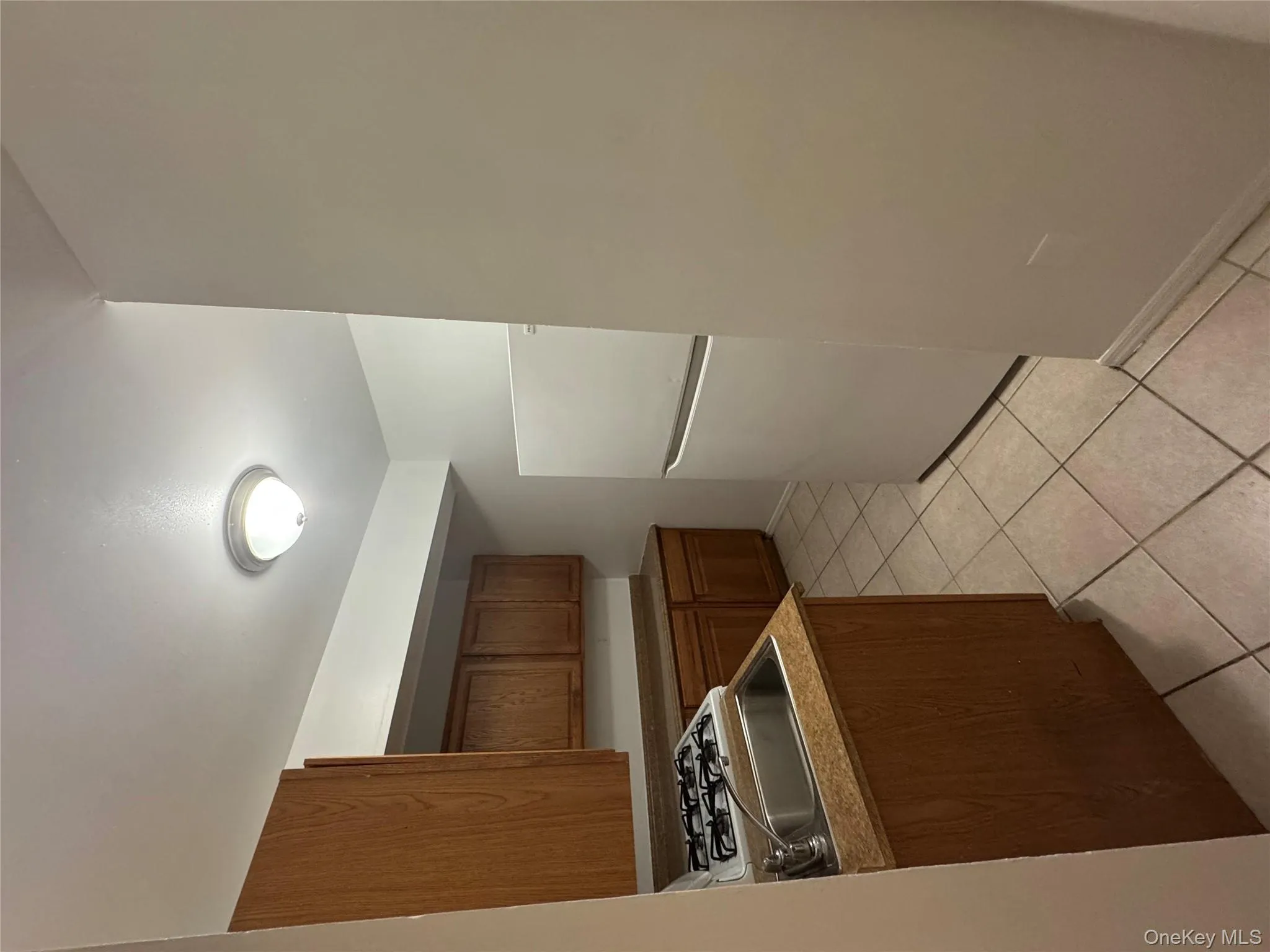 Kitchen featuring white refrigerator, light tile patterned flooring, and brown cabinets Kitchen featuring white refrigerator, light tile patterned flooring, and brown cabinets