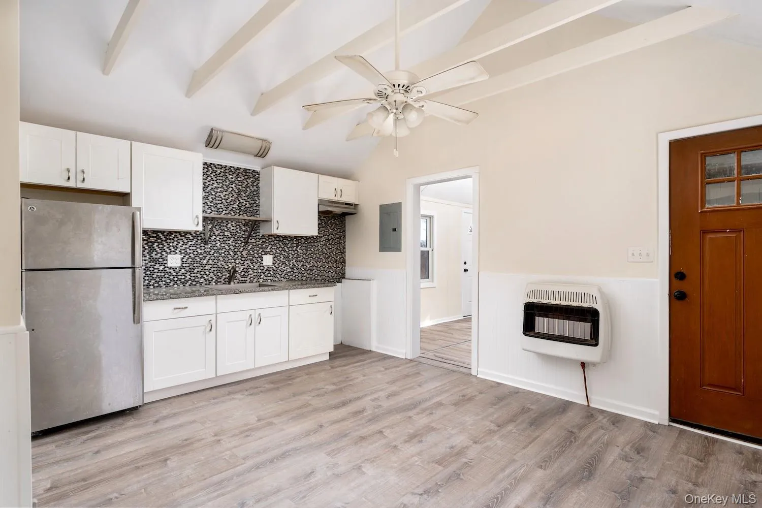 Kitchen featuring freestanding refrigerator, white cabinetry, wainscoting, light wood-style floors, and heating unit Kitchen featuring freestanding refrigerator, white cabinetry, wainscoting, light wood-style floors, and heating unit