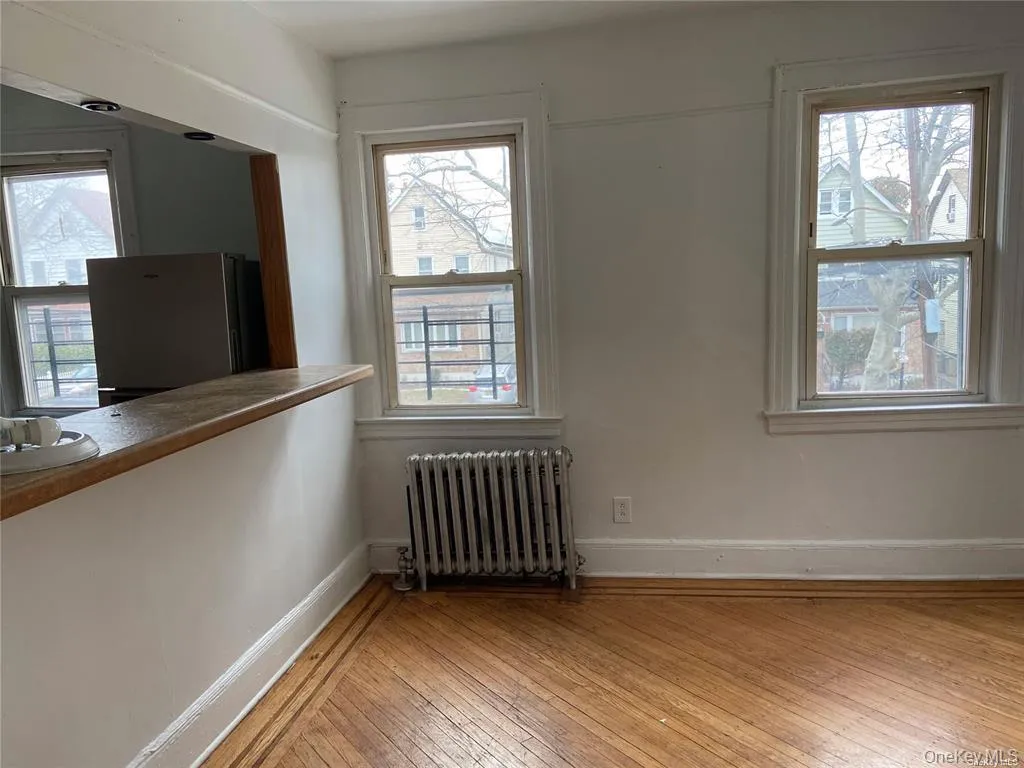 Unfurnished room featuring radiator heating unit, light wood-type flooring, and plenty of natural light Unfurnished room featuring radiator heating unit, light wood-type flooring, and plenty of natural light