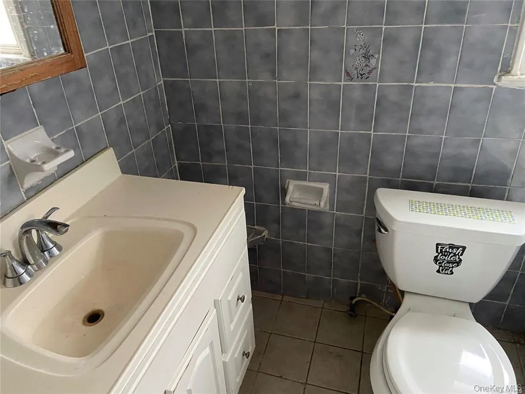 Bathroom featuring vanity, dark tile patterned flooring, and tile walls Bathroom featuring vanity, dark tile patterned flooring, and tile walls