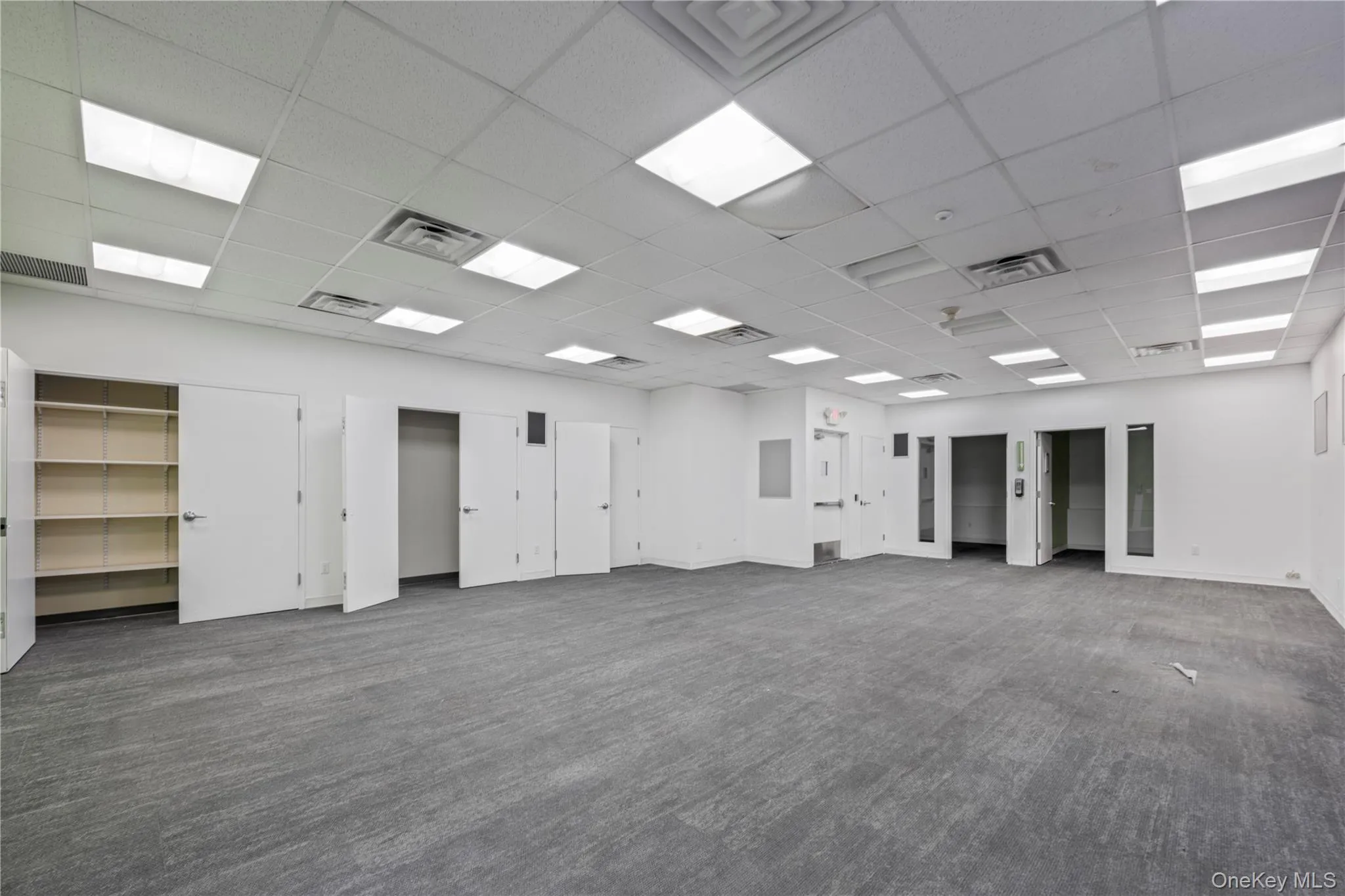 Empty room featuring a drop ceiling and dark colored carpet Empty room featuring a drop ceiling and dark colored carpet
