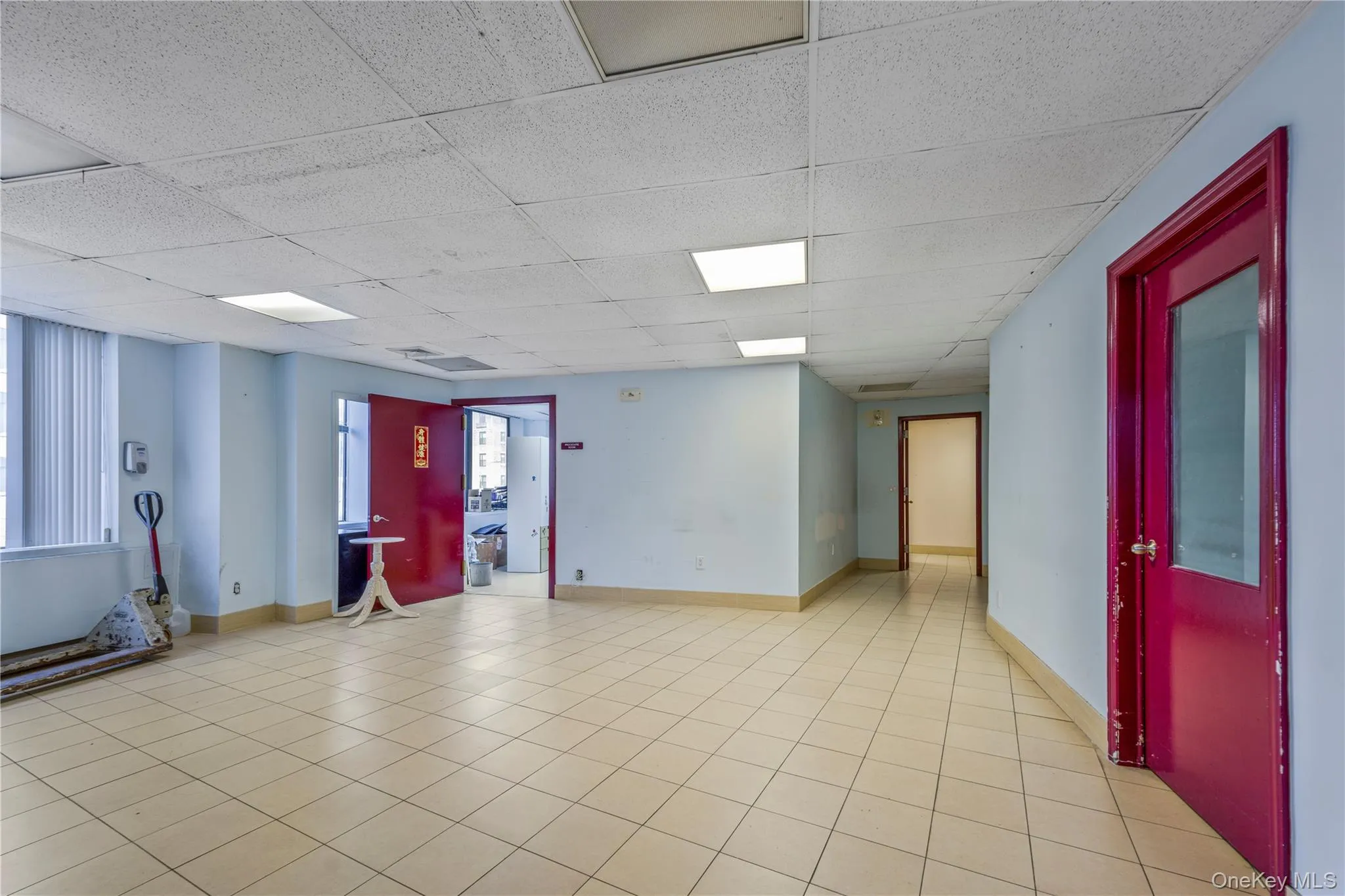 Empty room featuring a paneled ceiling and light tile patterned floors Empty room featuring a paneled ceiling and light tile patterned floors