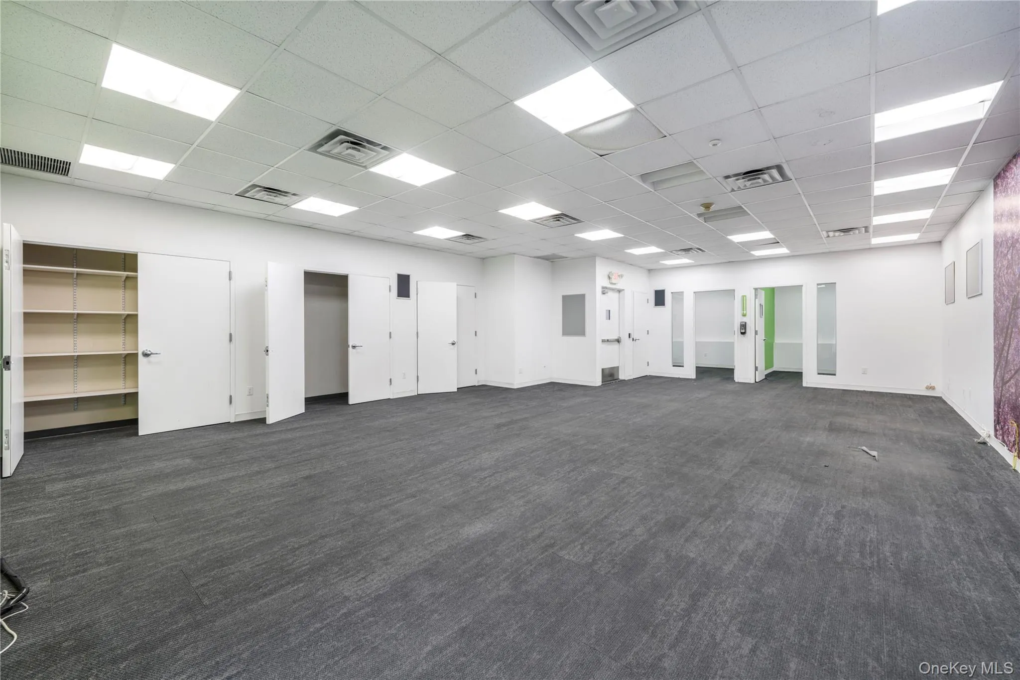 Empty room with a drop ceiling and dark carpet Empty room with a drop ceiling and dark carpet