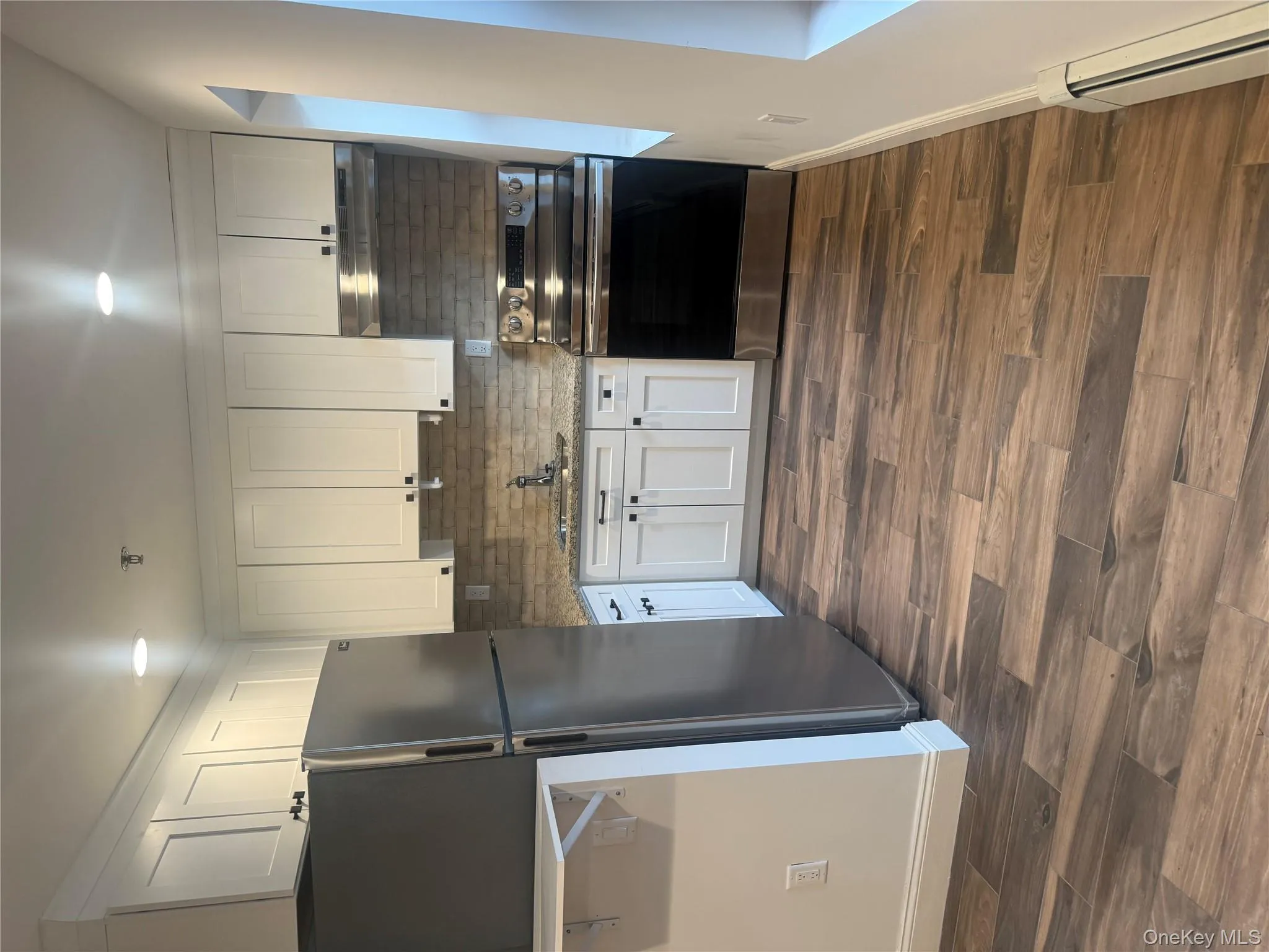 Kitchen featuring white cabinets, range, stainless steel fridge, a baseboard heating unit, and dark wood-style floors Kitchen featuring white cabinets, range, stainless steel fridge, a baseboard heating unit, and dark wood-style floors