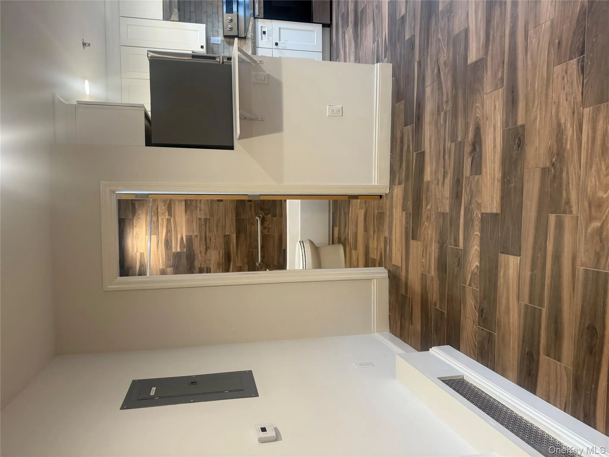 Kitchen with white cabinets, wood finish floors, stove, electric panel, and decorative backsplash Kitchen with white cabinets, wood finish floors, stove, electric panel, and decorative backsplash