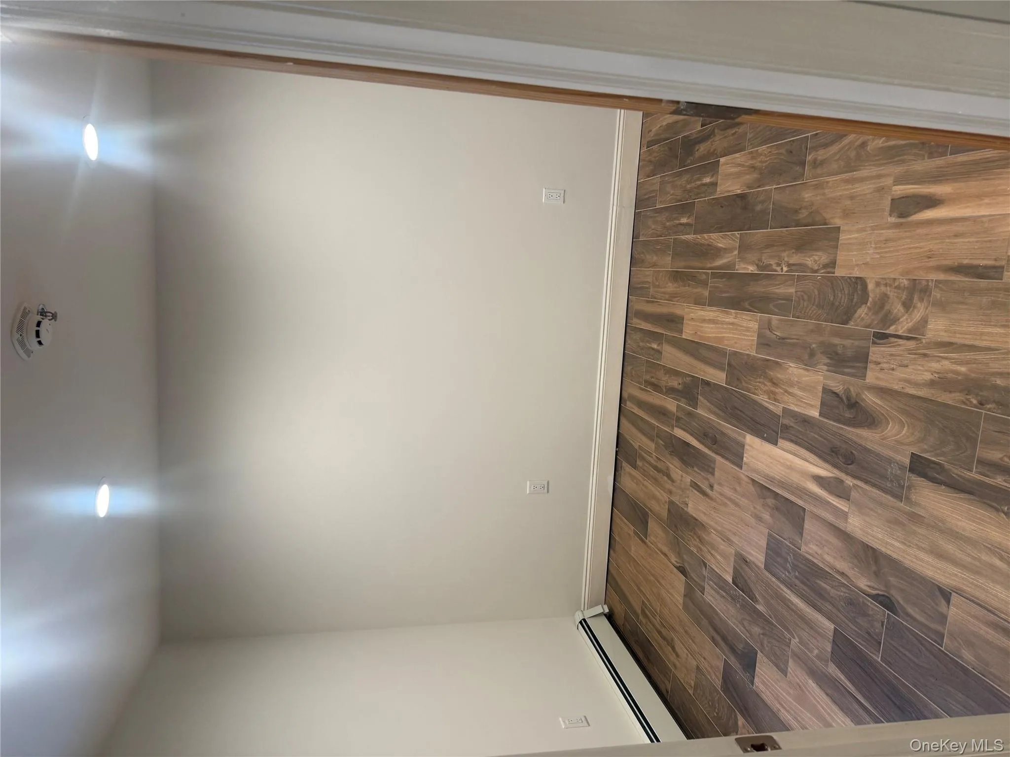Spare room with wood tiled floors, a baseboard radiator, recessed lighting, and a smoke detector Spare room with wood tiled floors, a baseboard radiator, recessed lighting, and a smoke detector