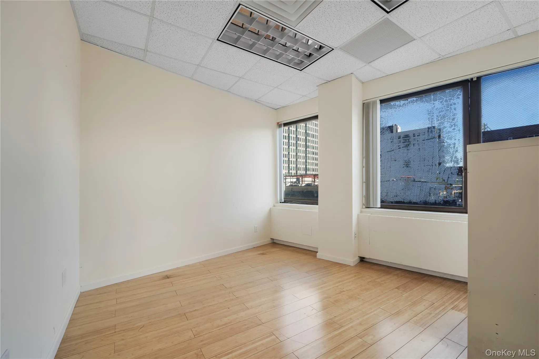 Empty room with light wood-style flooring and a drop ceiling Empty room with light wood-style flooring and a drop ceiling