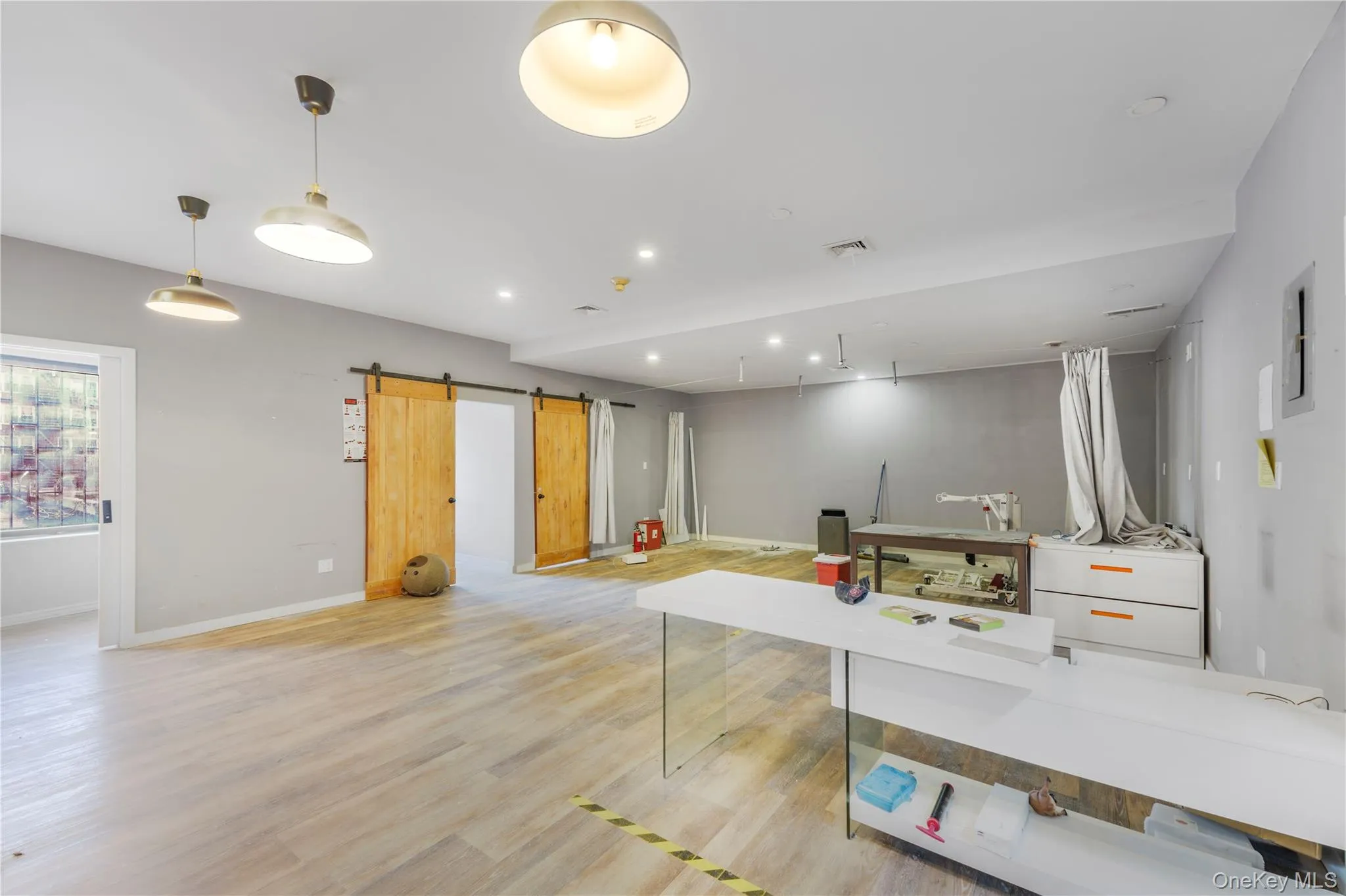 Basement with a barn door, recessed lighting, and light wood-type flooring Basement with a barn door, recessed lighting, and light wood-type flooring