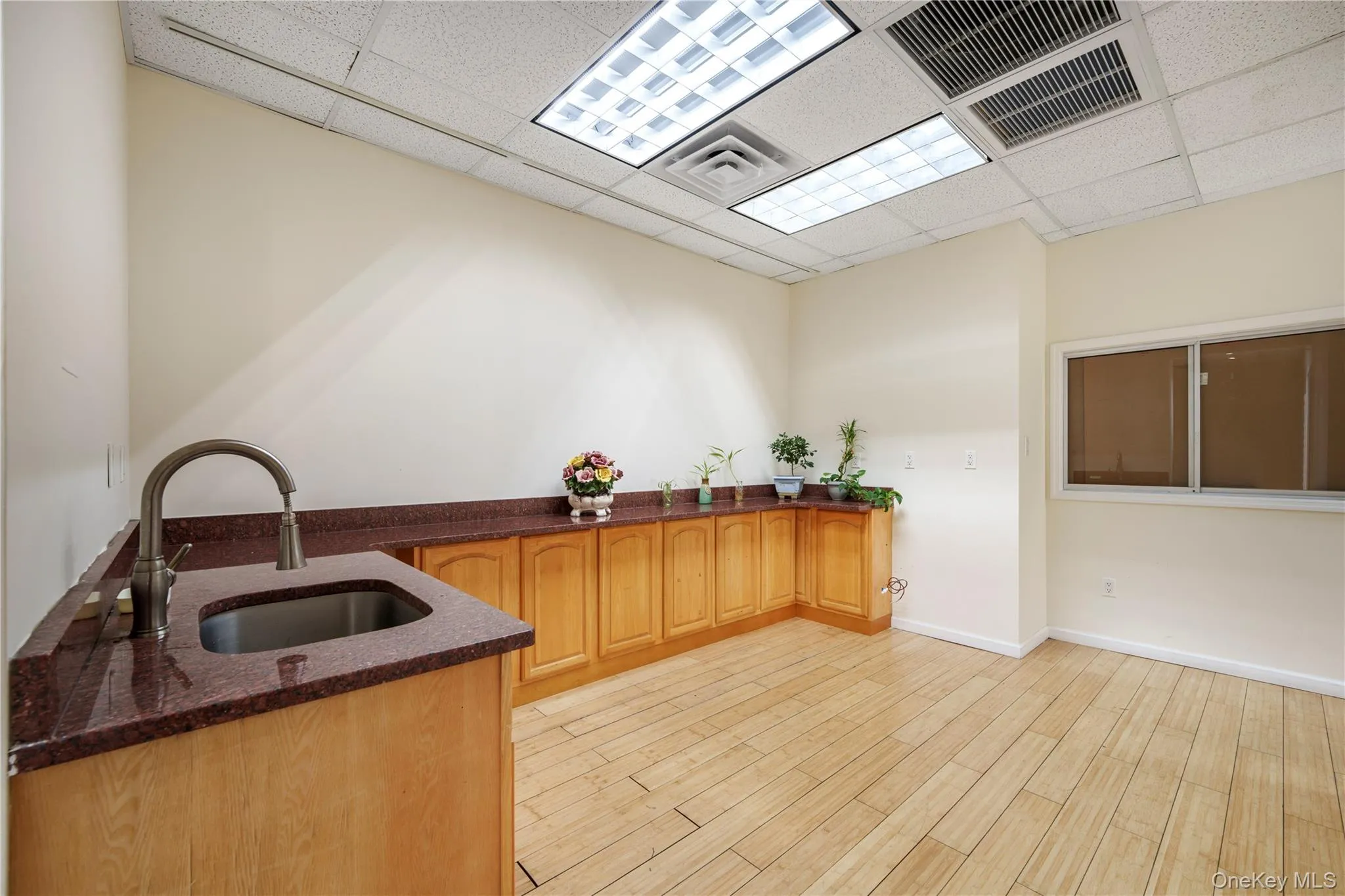 Kitchen featuring dark stone counters, wood finish floors, and a drop ceiling Kitchen featuring dark stone counters, wood finish floors, and a drop ceiling