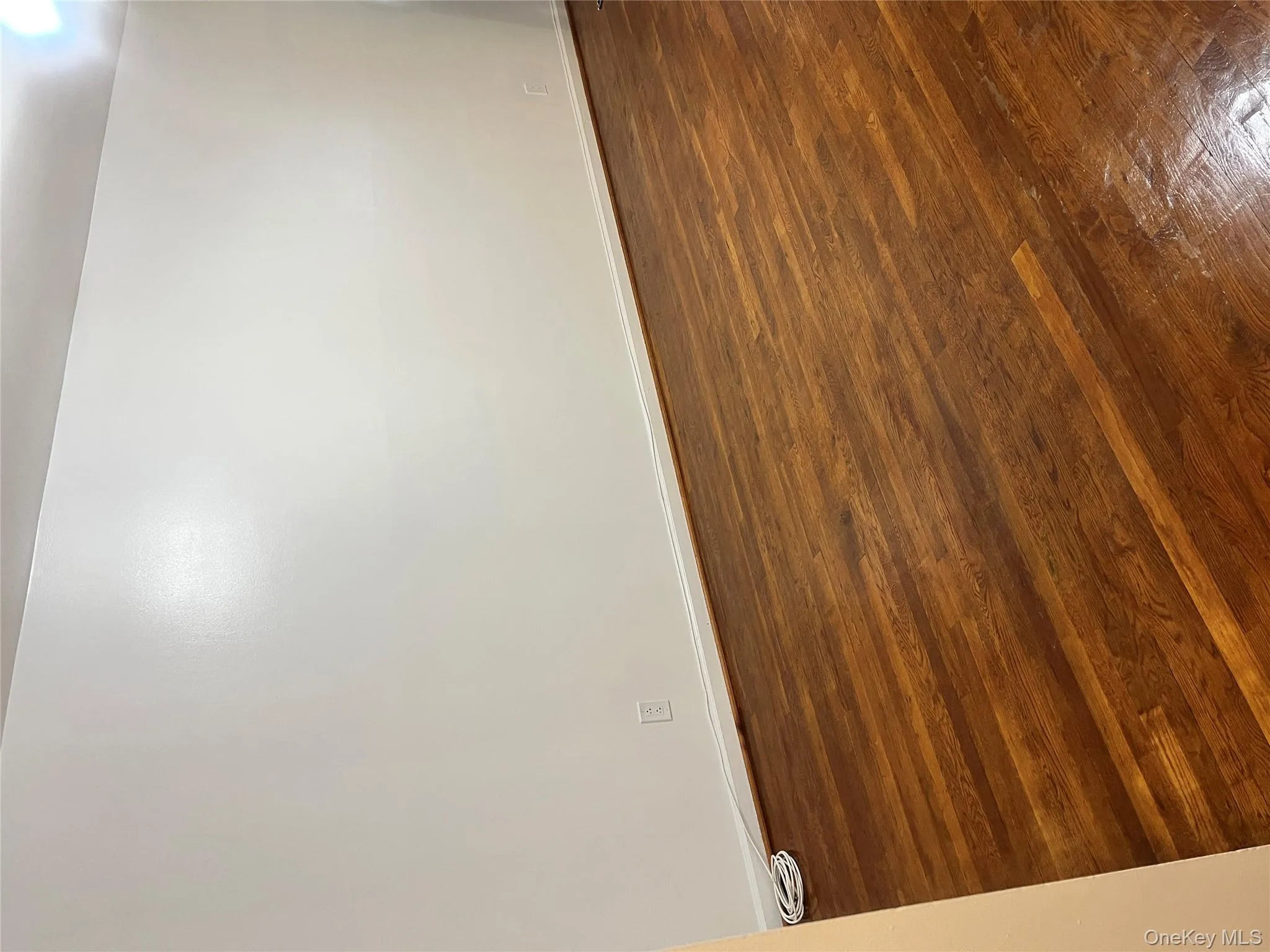 Spare room with dark wood-type flooring and baseboards Spare room with dark wood-type flooring and baseboards