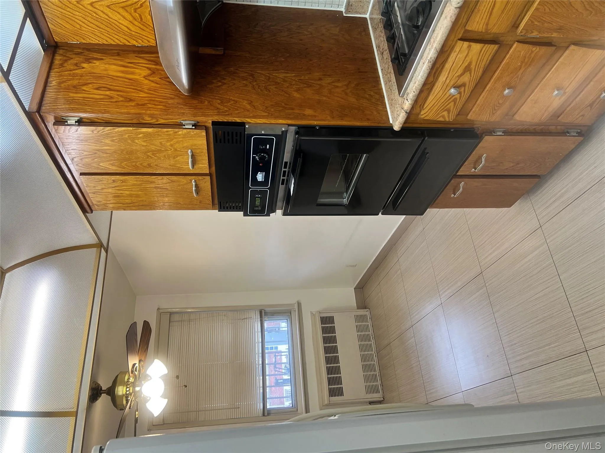 Kitchen with brown cabinets, ceiling fan, a warming drawer, radiator heating unit, and oven Kitchen with brown cabinets, ceiling fan, a warming drawer, radiator heating unit, and oven