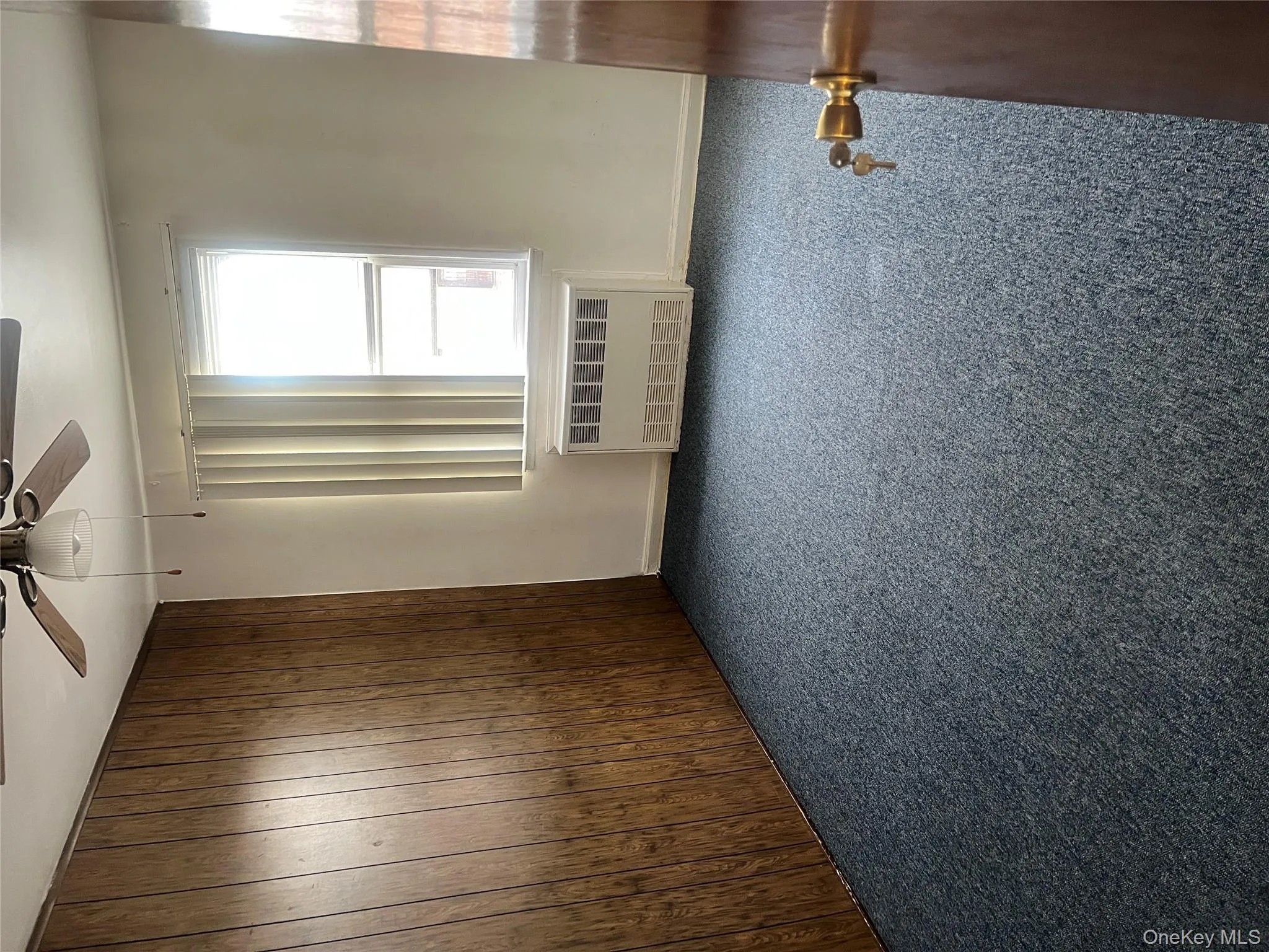 Unfurnished room with radiator, dark carpet, ceiling fan, and wood walls Unfurnished room with radiator, dark carpet, ceiling fan, and wood walls