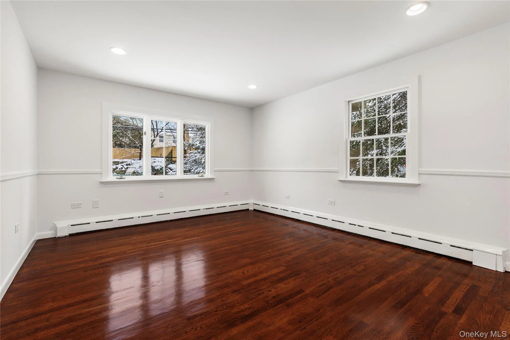 Unfurnished room featuring dark wood finished floors, baseboard heating, and recessed lighting Unfurnished room featuring dark wood finished floors, baseboard heating, and recessed lighting