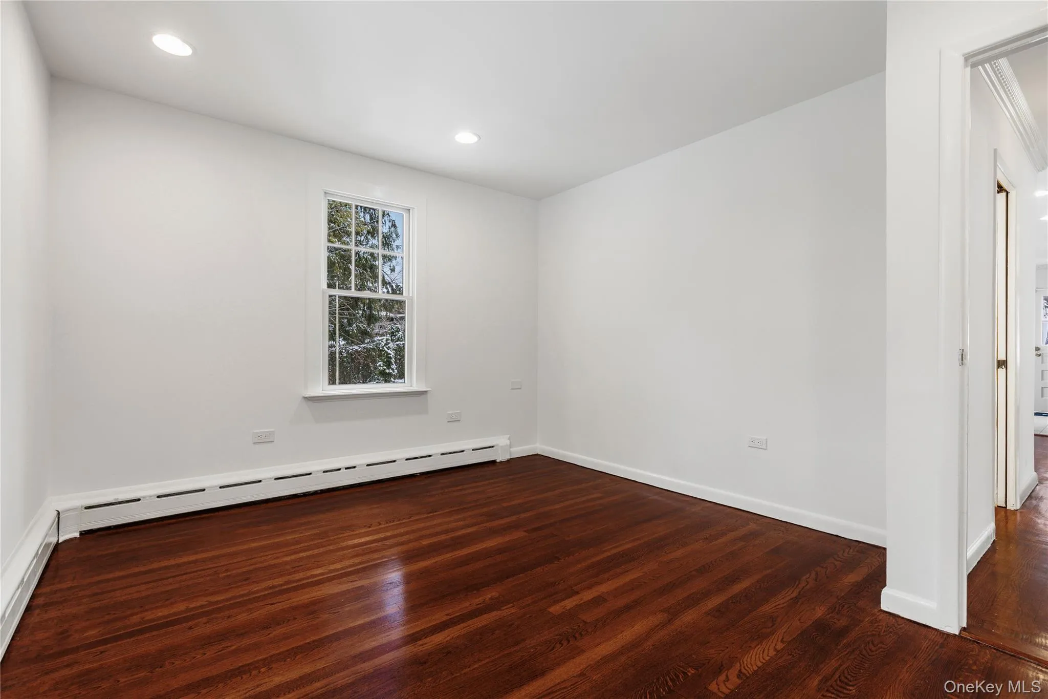 Unfurnished room featuring baseboard heating, dark wood-style flooring, a baseboard heating unit, and recessed lighting Unfurnished room featuring baseboard heating, dark wood-style flooring, a baseboard heating unit, and recessed lighting