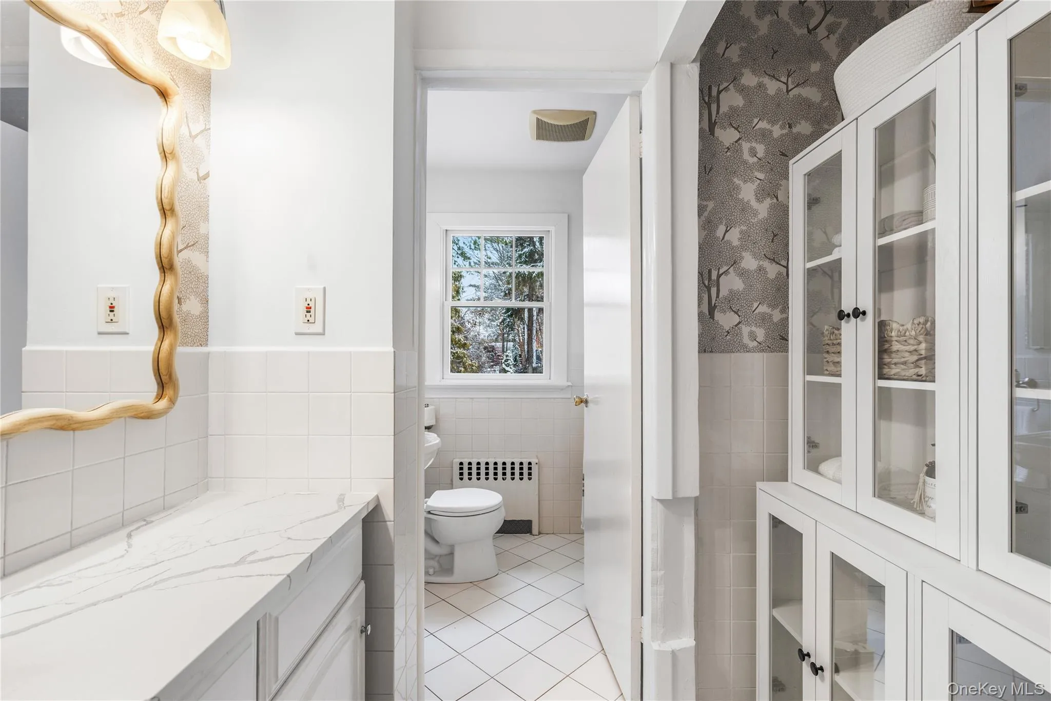 Bathroom with radiator, a wainscoted wall, light tile patterned floors, tile walls, and wallpapered walls Bathroom with radiator, a wainscoted wall, light tile patterned floors, tile walls, and wallpapered walls