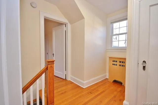 Hallway featuring an upstairs landing, radiator, and light wood-style flooring Hallway featuring an upstairs landing, radiator, and light wood-style flooring