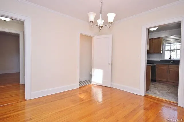 Unfurnished dining area featuring light wood-style flooring, ornamental molding, and a chandelier Unfurnished dining area featuring light wood-style flooring, ornamental molding, and a chandelier