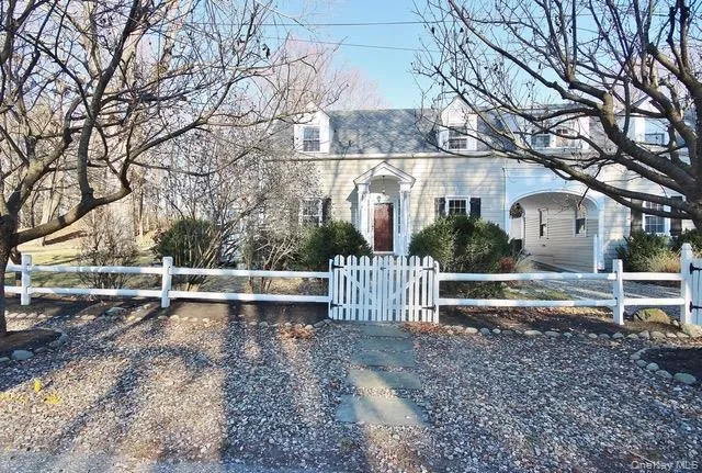 Colonial-style house featuring a fenced front yard and a gate Colonial-style house featuring a fenced front yard and a gate