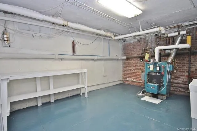 Unfinished basement featuring brick wall and a heating unit Unfinished basement featuring brick wall and a heating unit