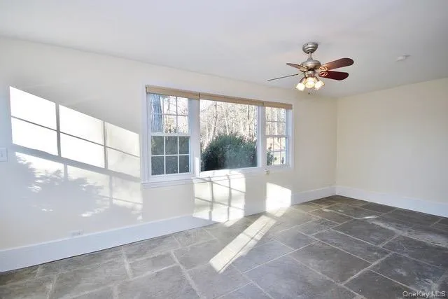 Unfurnished room with stone tile floors and a ceiling fan Unfurnished room with stone tile floors and a ceiling fan