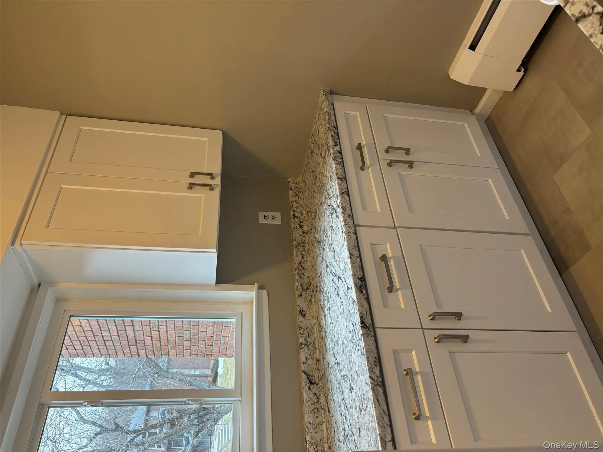 Kitchen with light stone countertops, white cabinetry, and baseboard heating Kitchen with light stone countertops, white cabinetry, and baseboard heating