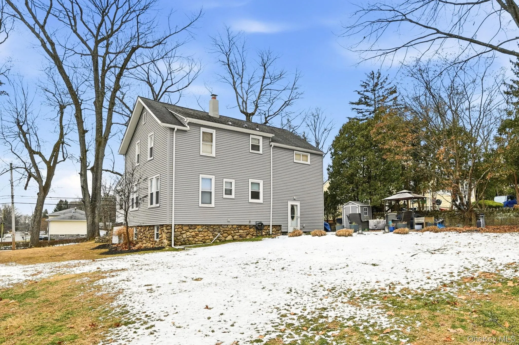 Snow covered rear of property with a chimney and an outbuilding Snow covered rear of property with a chimney and an outbuilding