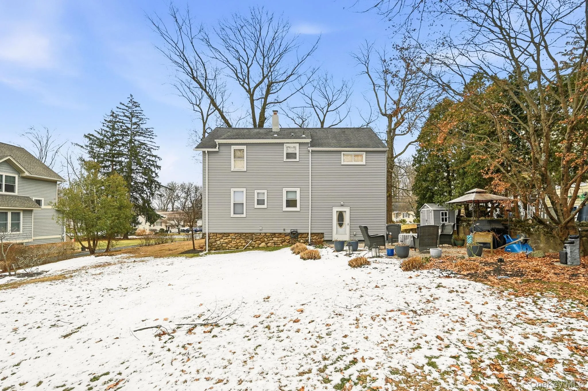 Snow covered rear of property with a patio area and a chimney Snow covered rear of property with a patio area and a chimney