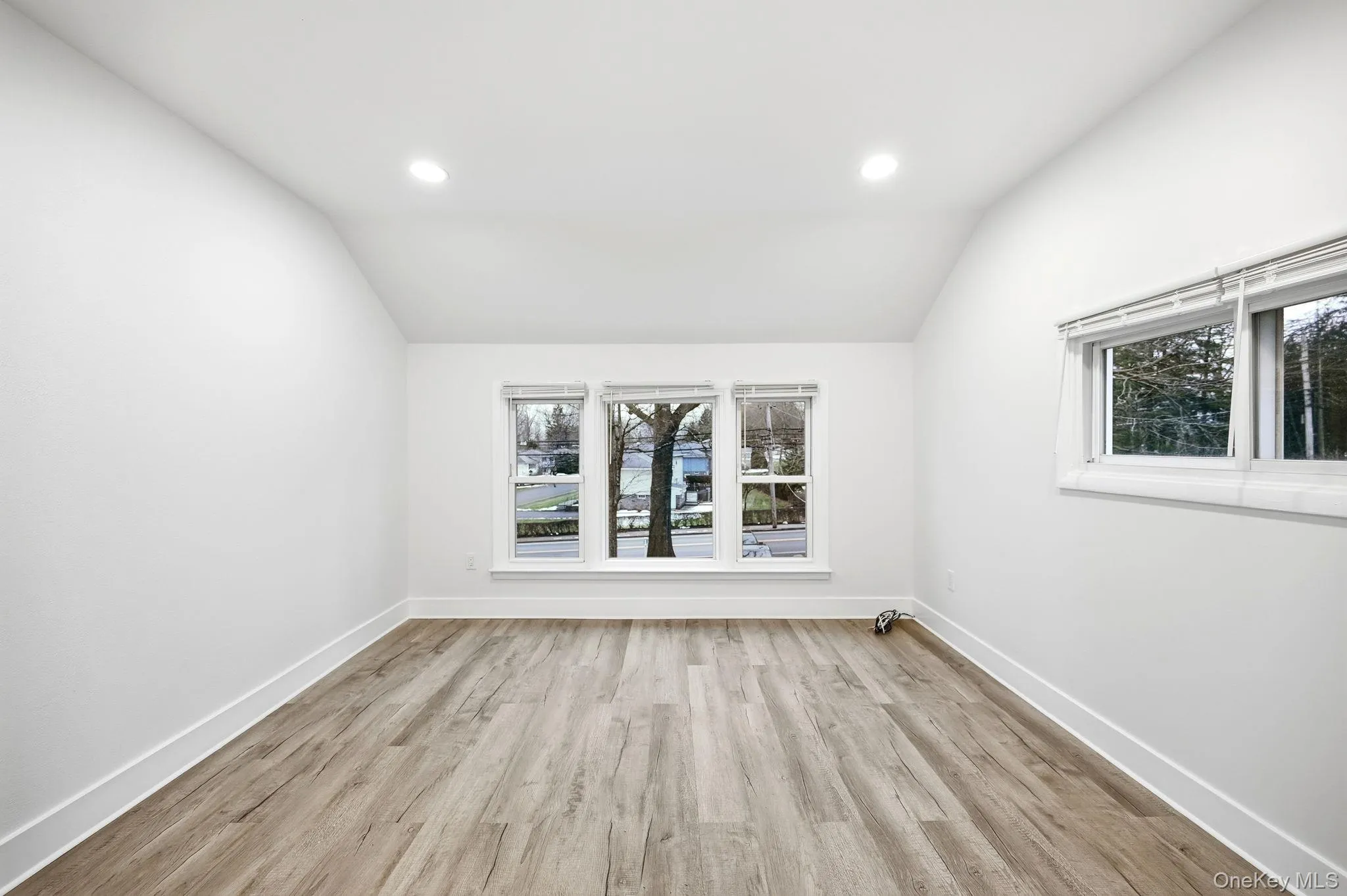 Spare room featuring light wood-style flooring, vaulted ceiling, and recessed lighting Spare room featuring light wood-style flooring, vaulted ceiling, and recessed lighting