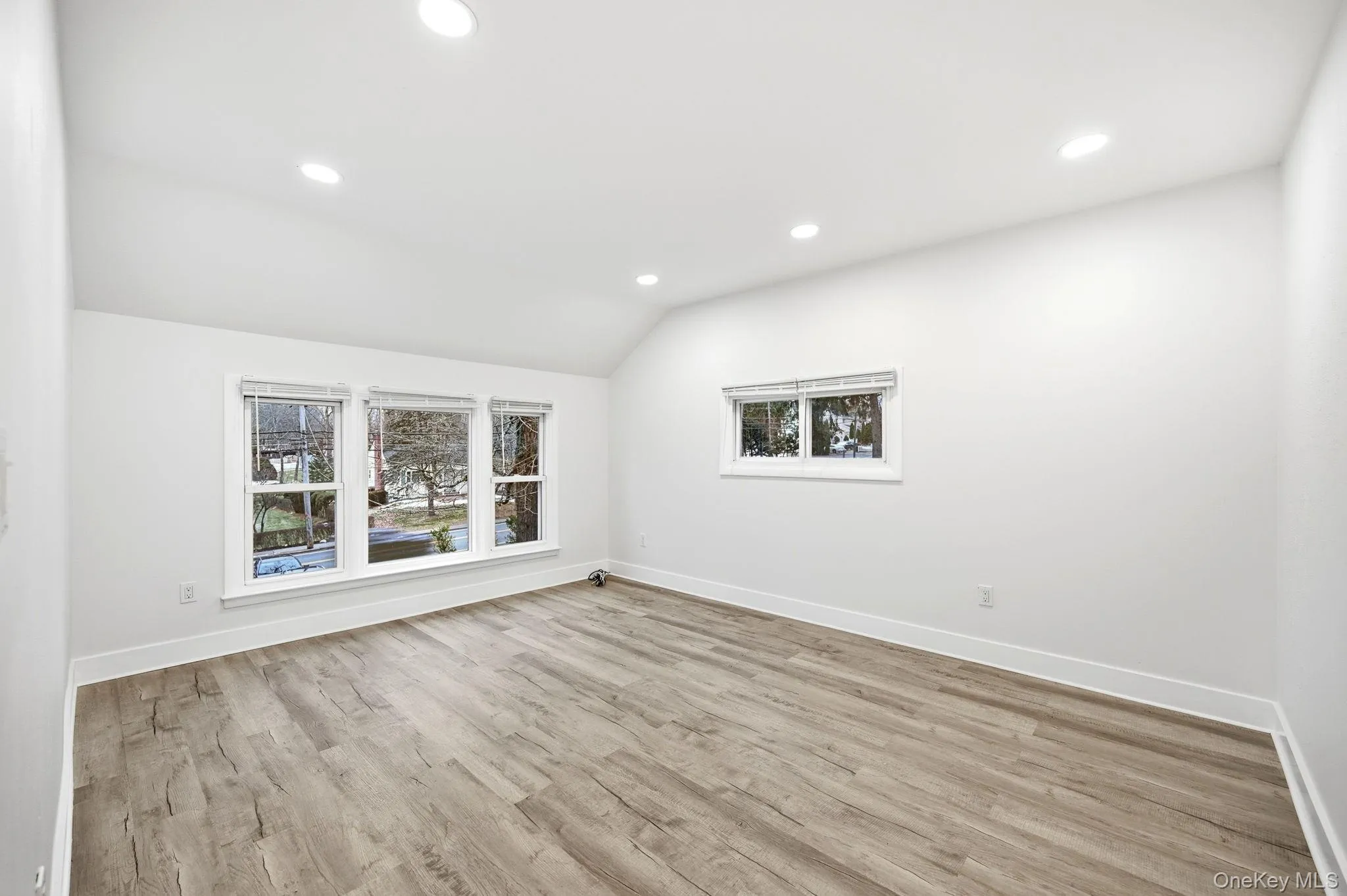 Spare room featuring vaulted ceiling, light wood-style flooring, and recessed lighting Spare room featuring vaulted ceiling, light wood-style flooring, and recessed lighting